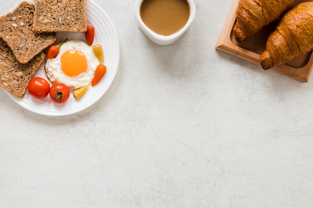 Foto gratuita huevo frito con cruasanes de pan y café con espacio de copia