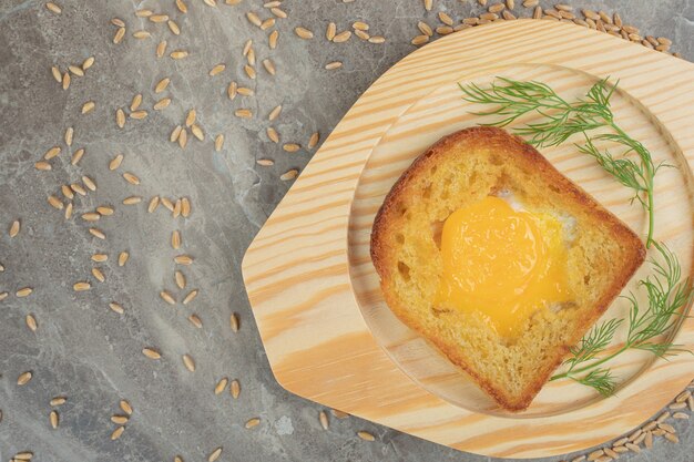Huevo frito dentro de una rebanada de pan tostado en placa de madera. Foto de alta calidad