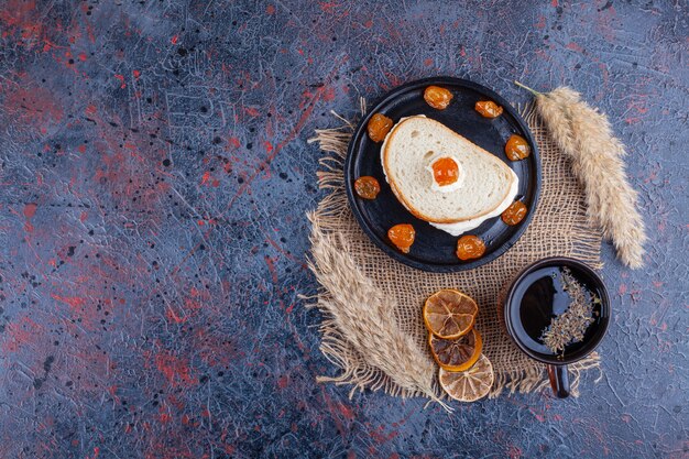 Huevo frito entre dos rebanadas de pan sobre una placa junto a una taza de té, sobre el fondo azul.