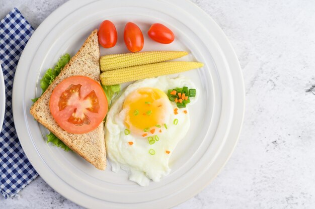 Un huevo frito que pone en una tostada, cubierto con semillas de pimiento con zanahorias, elote y cebolletas.