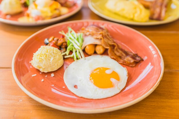 Huevo frito con salchicha bacaon jamón patata vegetal en placa