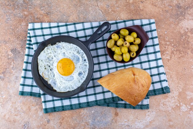 Huevo frito en sartén servido con aceitunas marinadas