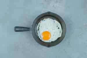 Foto gratuita huevo frito en una sartén sobre fondo de mármol. foto de alta calidad