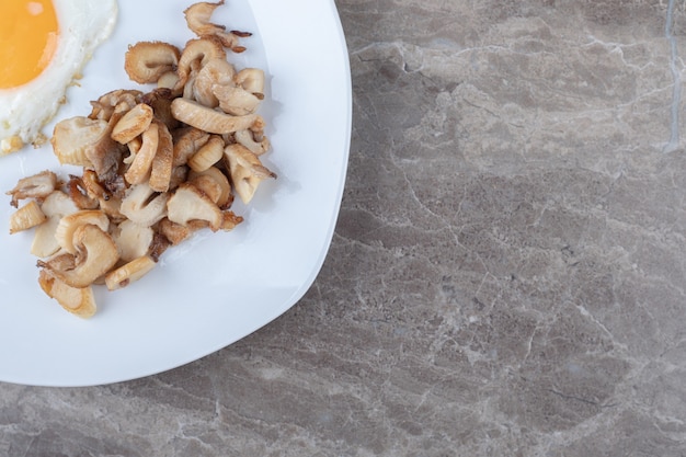 Foto gratuita huevo frito soleado y champiñones en un plato blanco.