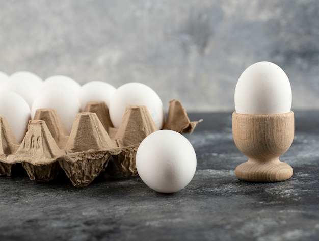 Huevo de gallina crudo en huevera con eggbox sobre una superficie de mármol.