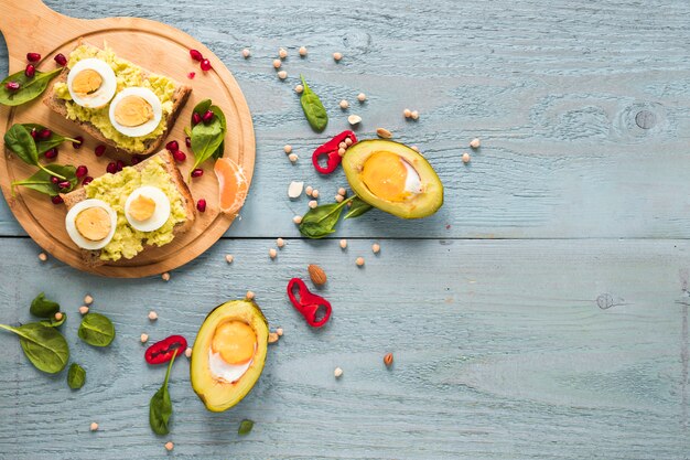 Huevo orgánico al horno en aguacate con pan tostado con huevo cocido en una tabla para cortar