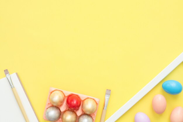 Huevo de Pascua colorido plano de la vista superior de la endecha pintado en la composición de los colores en colores pastel con el pincel en amarillo