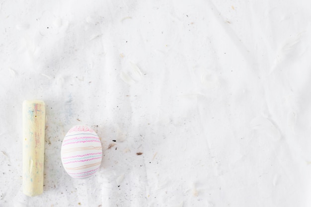 Huevo de Pascua con patrón cerca de plumas y tiza en textil