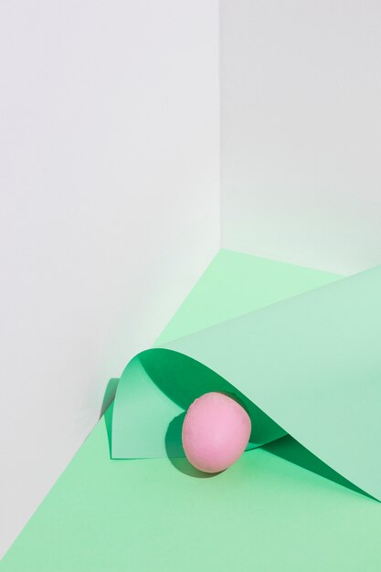 Huevo de Pascua rosa pequeño con hoja de papel sobre mesa