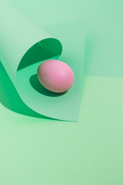 Huevo de Pascua rosa pequeño con papel enrollado en mesa