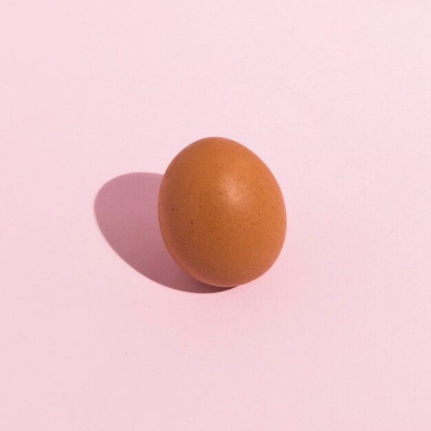 Huevo pequeño de gallina marrón en mesa rosa