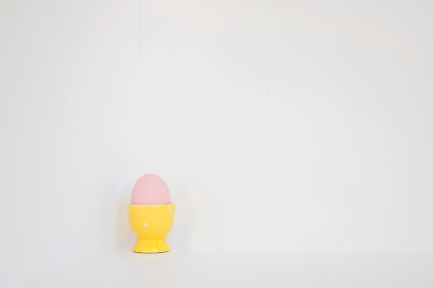 Huevo rosado en soporte amarillo