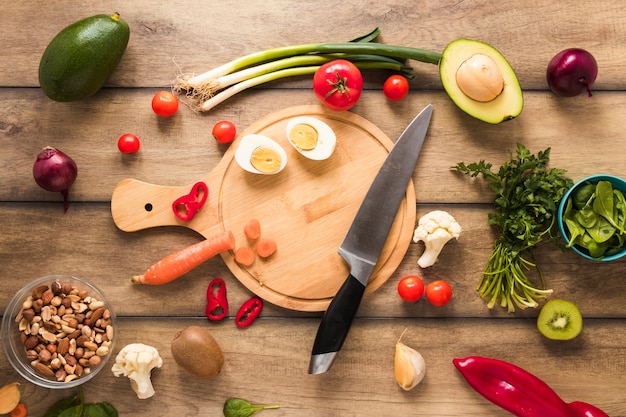 Huevo; Verduras e ingredientes frescos con cuchillo en mesa de madera