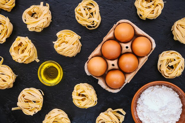 Huevos y aceite en medio de pasta y harina