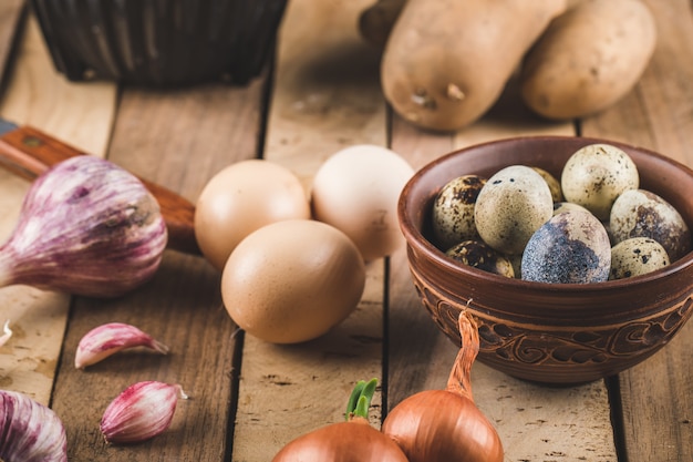 Huevos, ajo y cebolla en una tabla de madera.