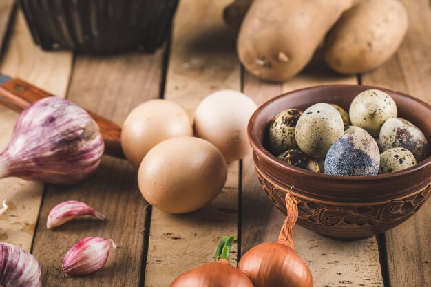 Huevos, ajo y cebolla en una tabla de madera.
