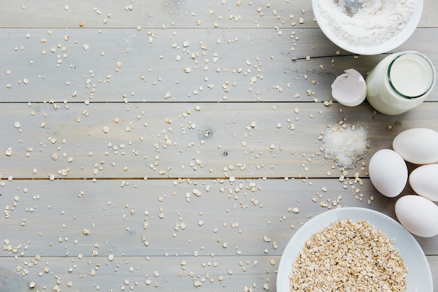 Foto gratuita huevos; avena; leche; harina; y azúcar sobre fondo de madera