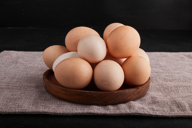 Huevos en bandeja de madera sobre papel de cocina.