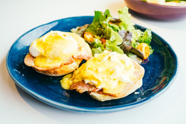 Huevos benedictinos con jamón y salsa encima.