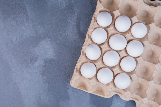 Foto gratuita huevos blancos en bandeja de cartón.