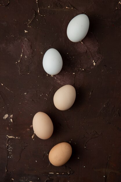 huevos blancos y marrones en la mesa granate