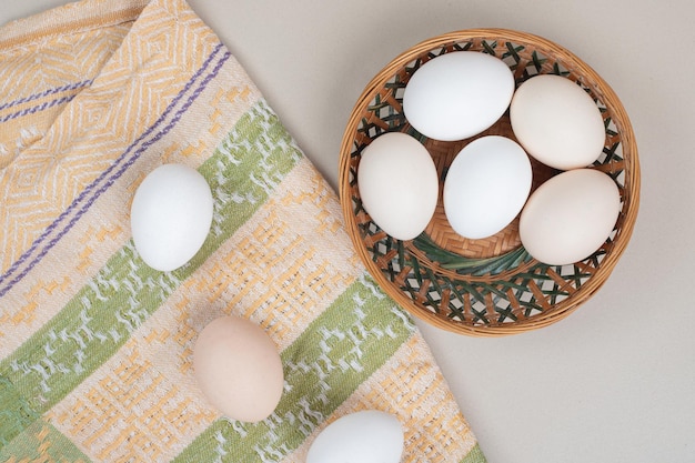 Huevos blancos de pollo frescos en cesta de mimbre.