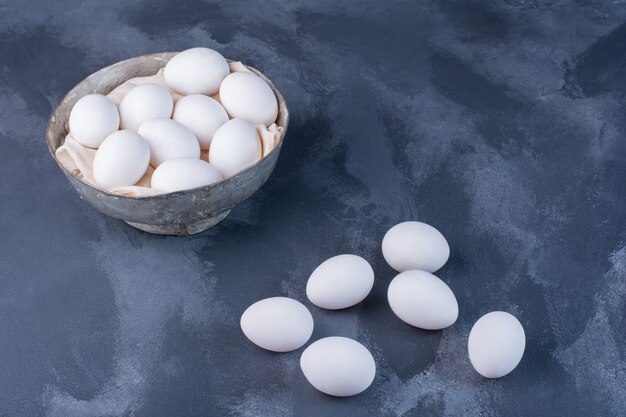 Huevos blancos en una taza albólica en azul.