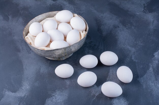 Huevos blancos en una taza albólica en azul.