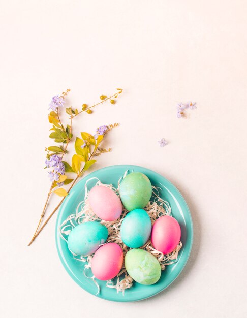 Huevos brillantes en un plato cerca de una ramita de flores