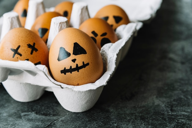 Huevos con caras de Halloween en la foto existente en cartón