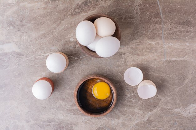 Huevos, cáscaras de huevo y yema de huevo en una taza de madera