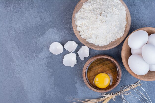 Huevos, cáscaras de huevo y yema de huevo en una taza de madera