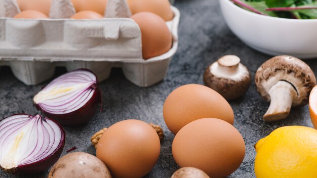 Huevos; cebolla a la mitad; seta; Limón y huevos sobre encimera de cocina gris.