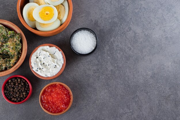 Huevos cocidos en rodajas con especias colocados sobre fondo de piedra.