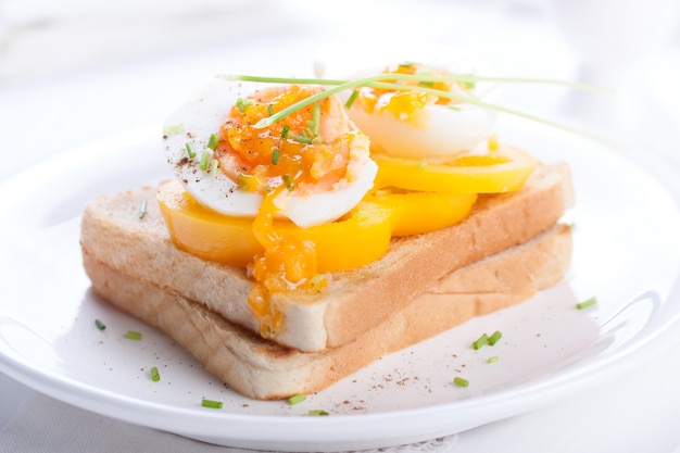 Huevos cocidos con tomate sobre rebanada de pan