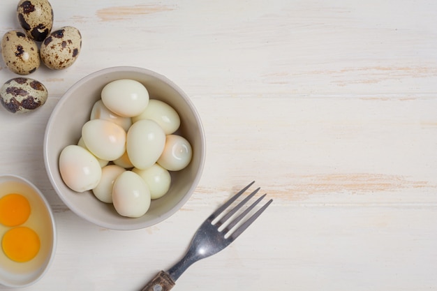 Huevos de codorniz cocidos en la superficie de madera blanca.