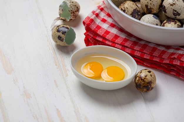 Huevos de codorniz frescos en la superficie de madera blanca.