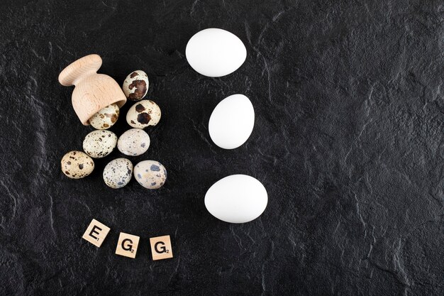 Huevos de codorniz y gallina sobre superficie negra.