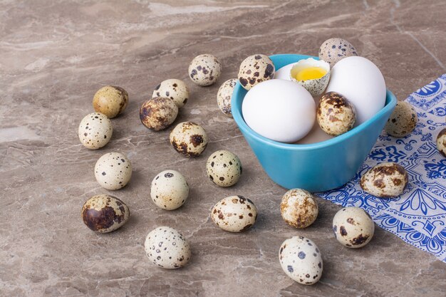 Huevos de codorniz y gallina en una taza azul