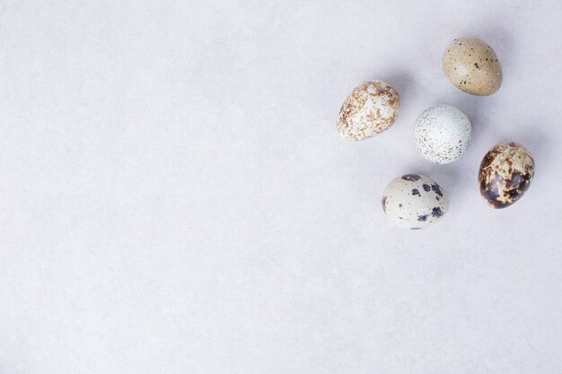 Huevos de codorniz orgánicos sobre superficie blanca.