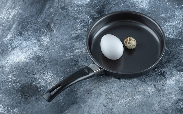 Huevos de codorniz y pollo orgánicos frescos en una sartén negra.