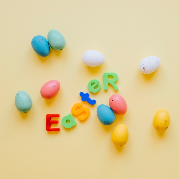 Foto gratuita huevos de colores y letras en la palabra pascua