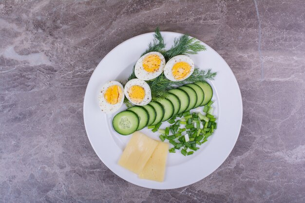 Huevos duros con ensalada verde en un plato blanco.