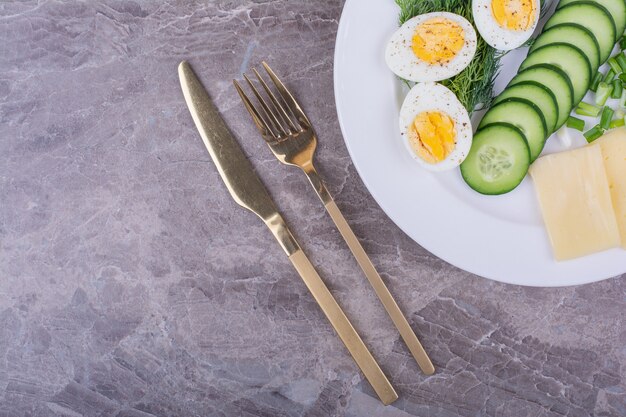 Huevos duros con ensalada verde en un plato blanco.