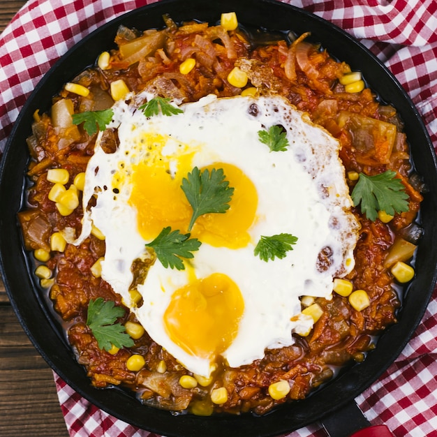 Huevos fritos con comida mexicana en una sartén.