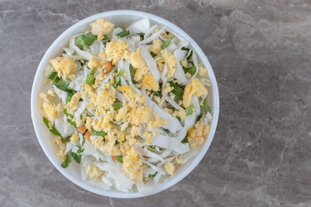 Huevos fritos y ensalada fresca en un tazón blanco.