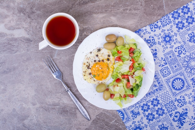 Huevos fritos y ensalada verde con una taza de té.