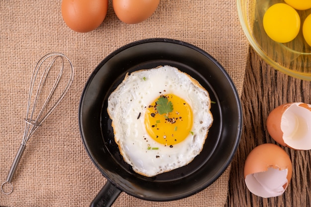 Huevos fritos en una sartén y huevos crudos, comida orgánica para una buena salud, alta en proteínas.