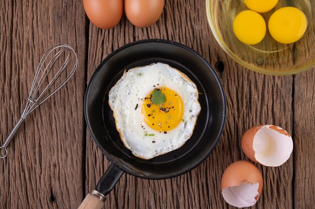 Huevos fritos en una sartén y huevos crudos, comida orgánica para una buena salud, alta en proteínas.