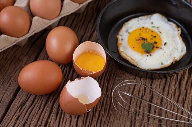 Huevos fritos en una sartén y huevos crudos, comida orgánica para una buena salud, alta en proteínas.